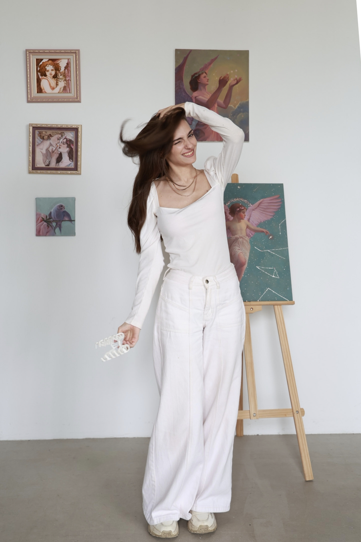 The artist lifting her hair among her paintings in the studio